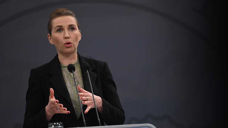 Frederiksen står bakom ett podium och talar i mikrofon.
