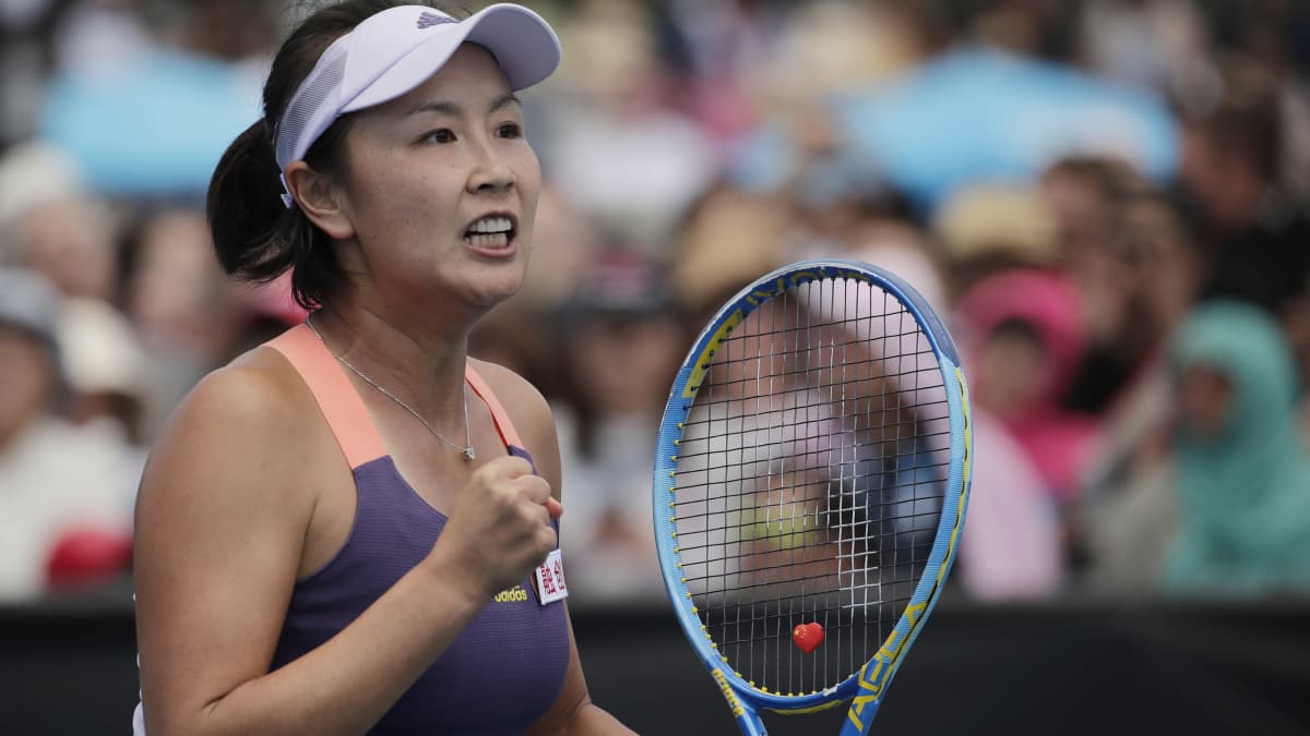 Peng Shuai pitää toista kättä nyrkissä ja toisessa kädessä tennismailaa.