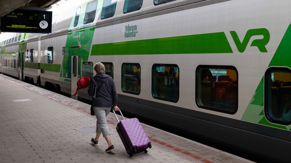 Matkustaja kävelemässä junalaiturilla Tampereen rautatieasemalla. Matkustaja etualalla ja VR pendoliino juna taustalla.