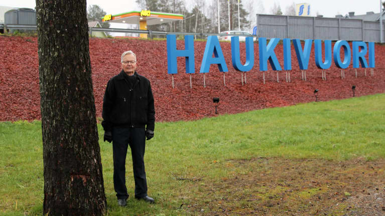 Haukivuoren aluejohtokunnan puheenjohtaja Leo Laukkanen Haukivuori-kyltin edustalla.