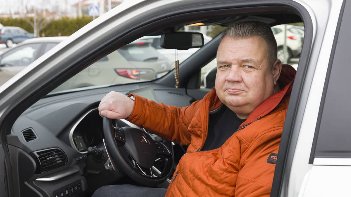 Mies istuu autossa.