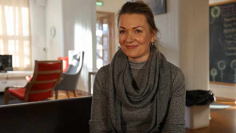 Lounais-Suomen Marttojen Johanna Heinonen hymyilee sohvalla asunnottomien asuntolassa. 
