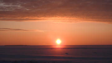 Auringonlasku jäisen meren taa. Iltaruskoa ja tasaista horisonttia. 