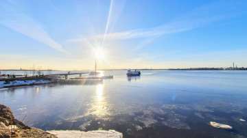 Aurinkoinen sää Suomenlahden rannalla. Saaristolaiva lipuu laituriin. 