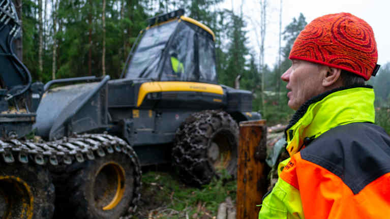 En man tittar mot en skogsmaskin.