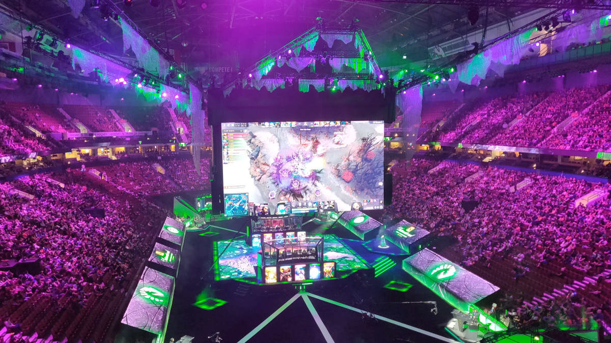 En arena fylld med folk. I mitten syns stora skärmar som visar dataspelet Dota 2. Det är en turnering i spelet på gång i arenan.