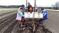 Nataliia Klymyk och Vitalii Vakar från Ukraina sitter bakpå en traktor och sätter potatis på en åker. Ruslan Klymyk kör traktorn.