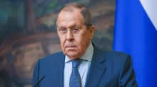 Sergej Lavrov klädd i kostym står framför en mikrofon. Han ser allvarlig ut. I bakgrunden Rysslands flagga.