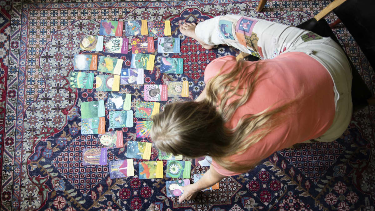 Liisa Kuusipalo laittaa värikkäitä kortteja lattiamatolle.