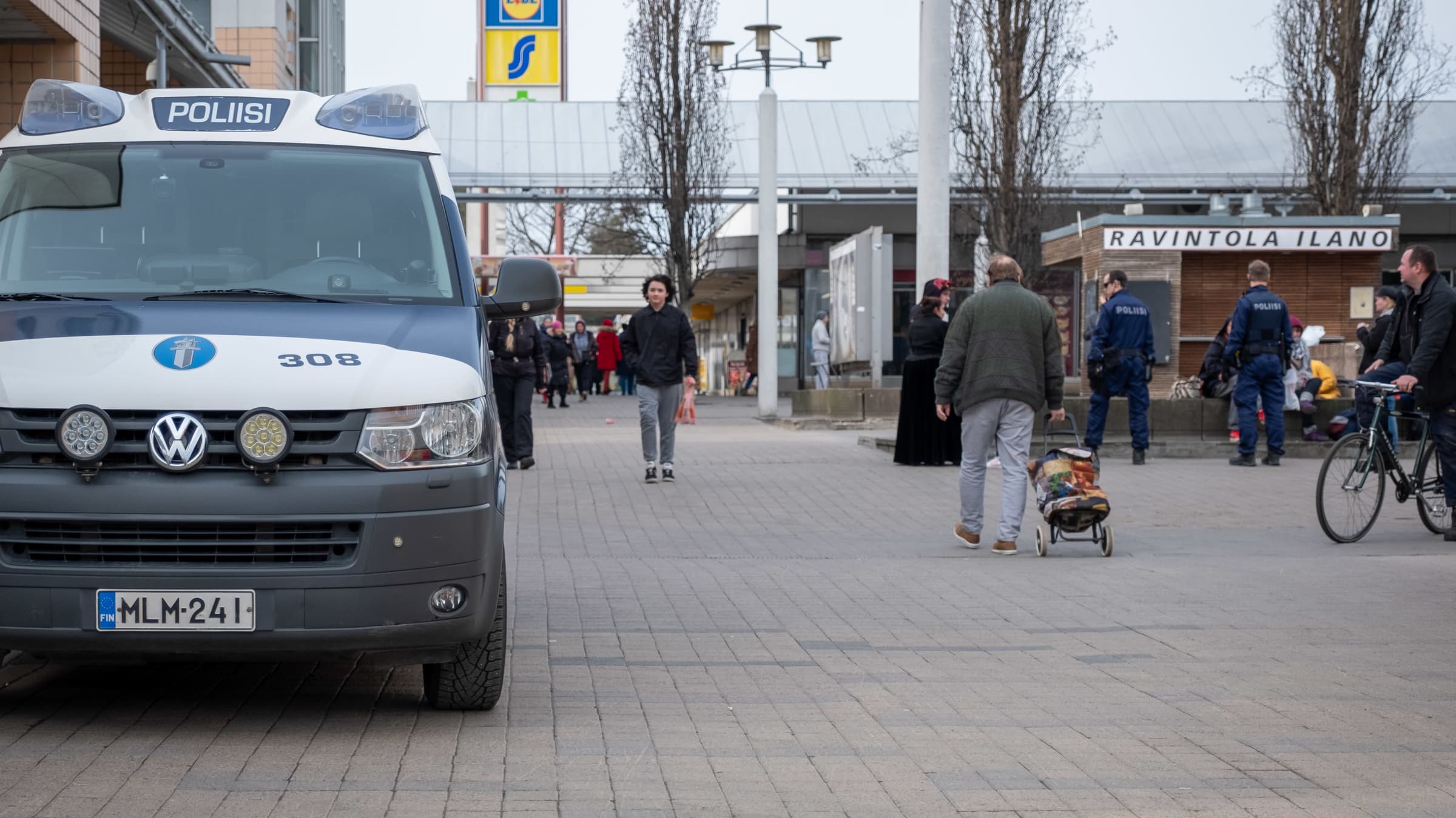 Ihmisiä ja poliisiauto Kontulan ostoskeskuksen pihalla.