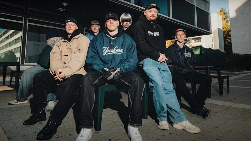 Velijay, Joosu J, Karu Indo, Will-Jam, Zombie Clit, Marko Kainulainen ja Tohtori Getto istuvat entisen ravintola Rentukan edessä Kortepohjassa Jyväskylässä.