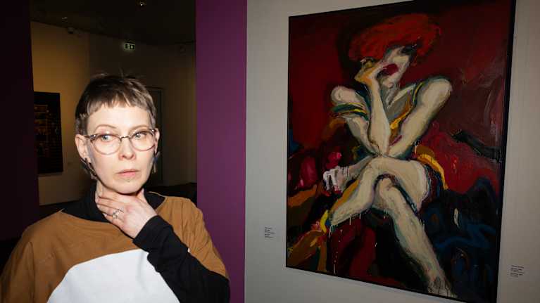 Nainen seisoo taideteoksen edessä.