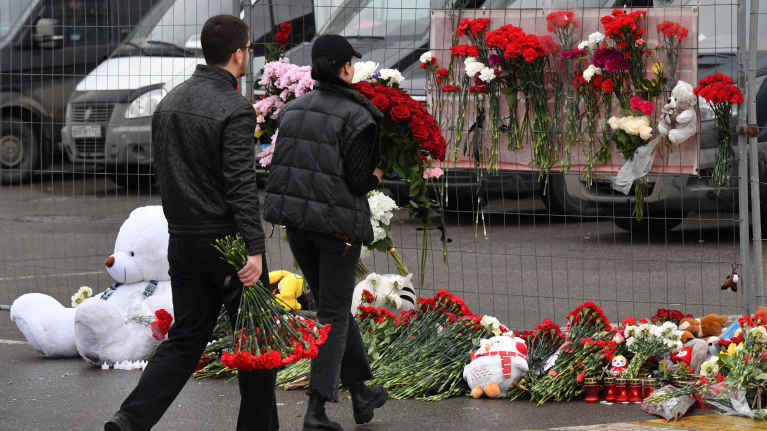 Ihmiset tuovat kukkia Moskovassa Crocus City Hall -konserttitalon parkkipaikalle terrori-iskun takia 23.3.2024.