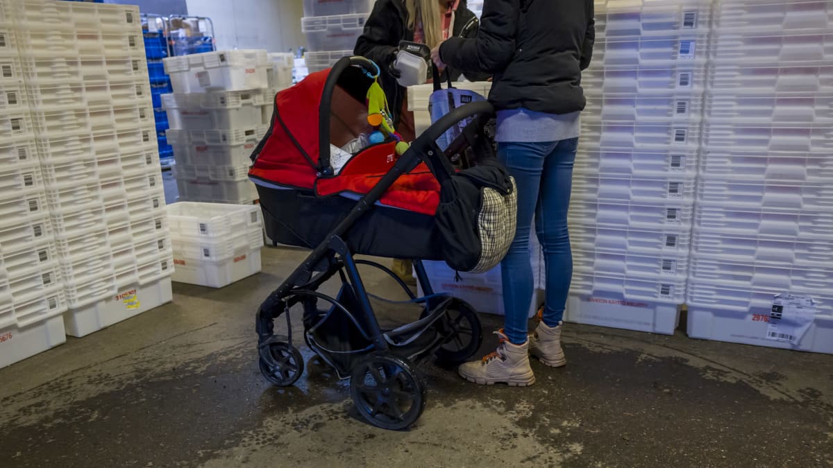 Nainen lastenrattaiden kanssa saamassa ruoka-apua Helsingin Myllypuron elintarvikejakelussa