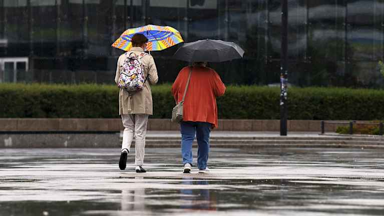 Two people were walking with umbrellas.