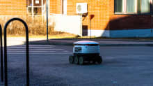 Valkoinen, laatikonmallinen kuljetusrobotti lähtee kuljettamaan ruokaostoksia Otaniemen Alepalta tilaajalle.