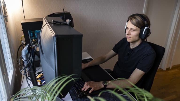 Juha-Pekka Palomaa pelaa tietokoneella kuulokkeet päässään. 