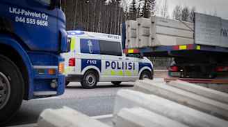Poliisiauto vahtii liikennettä kun rakennusmiehet asentavat betoniporsaita Valtatie 3. tiesululle  27.3.2020.