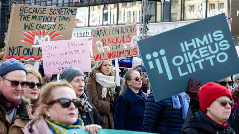 Naisten marssissa ihmiset pitävät kylttejä käsissään.