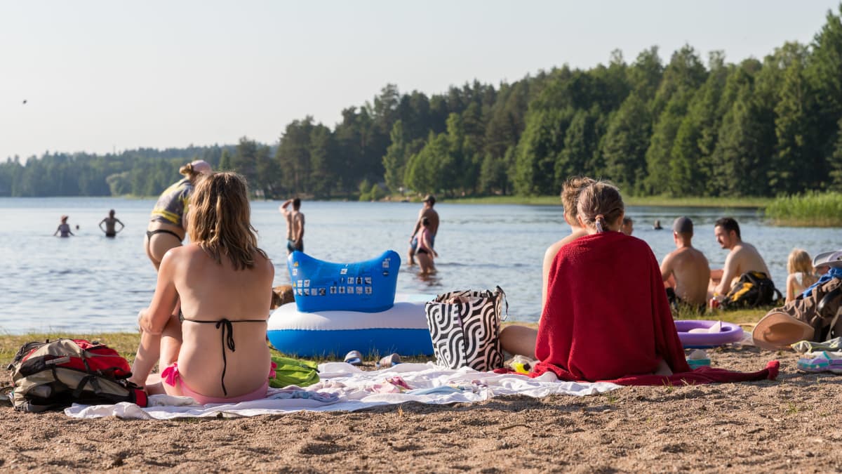 Paljon ihmisiä Tuomiojärven uimarannalla aurinkoisena kesäpäivänä.
