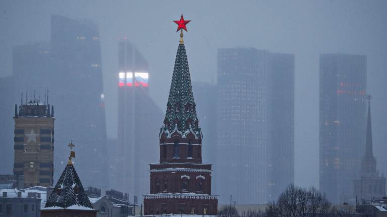 Красная звезда на вершине Кремлевской башни в Москве на фоне очертаний города.