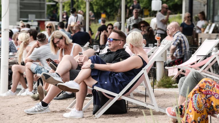  Ihmisiä nauttimassa terassilla Kaivopuiston rannassa Helsingissä.