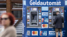 Mies nostaa käteistä automaatilta, jossa lukee saksaksi Geldautomat.