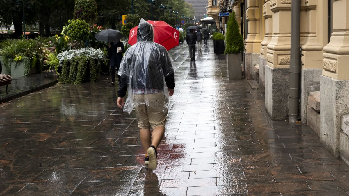 Sadetakkiin pukeutunut henkilö kävelee kadulla. 
