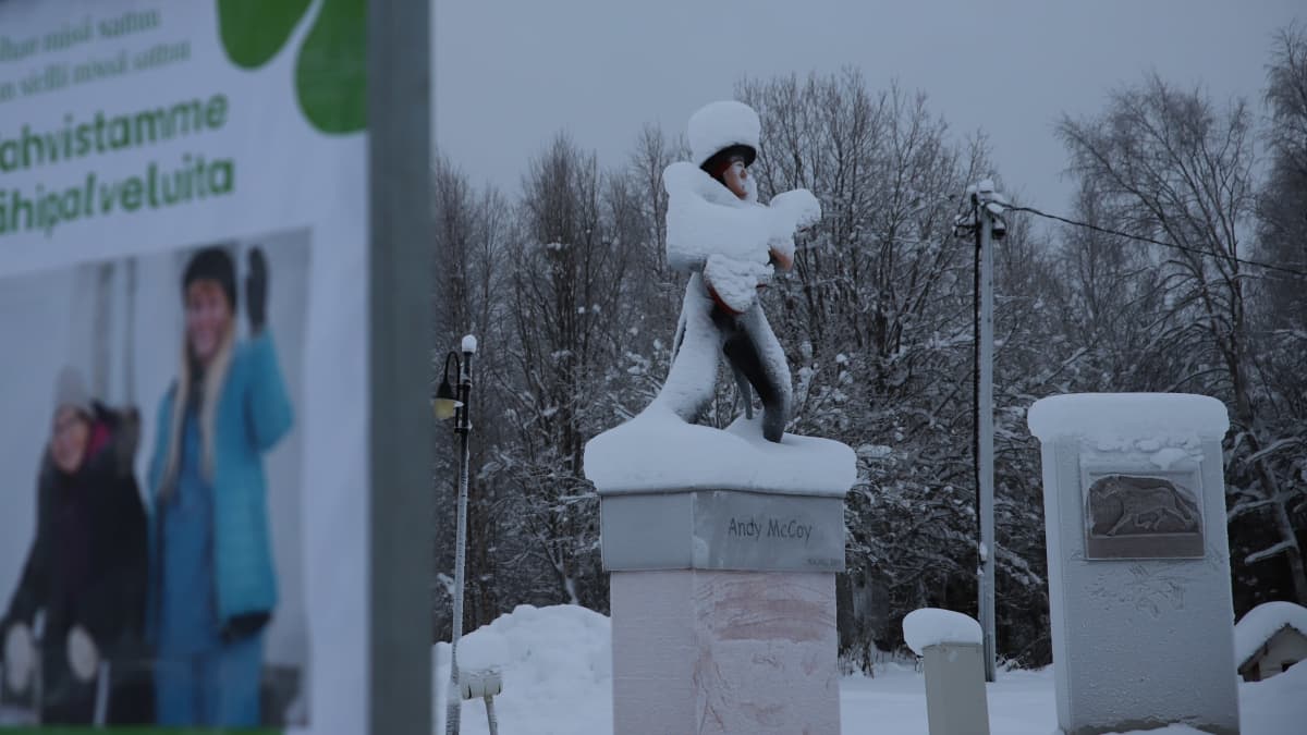 vaalimainos ja lumenpeittämä Andy Mc Coyn patsas Pelkosenniemellä