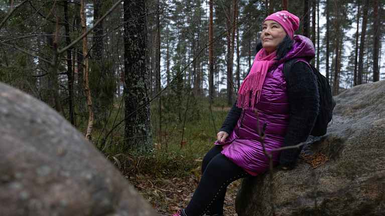 Nainen istuu kivellä.