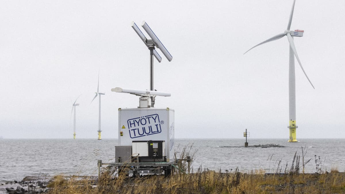 Tuulivoimala Porin Tahkoluossa, tuulimyllyt pyörivät merellä. Kuvan edustalla on lintututka, joka ilmoittaa, jos voimalat täytyy pysäyttää lähestyvän lintuparven vuoksi.