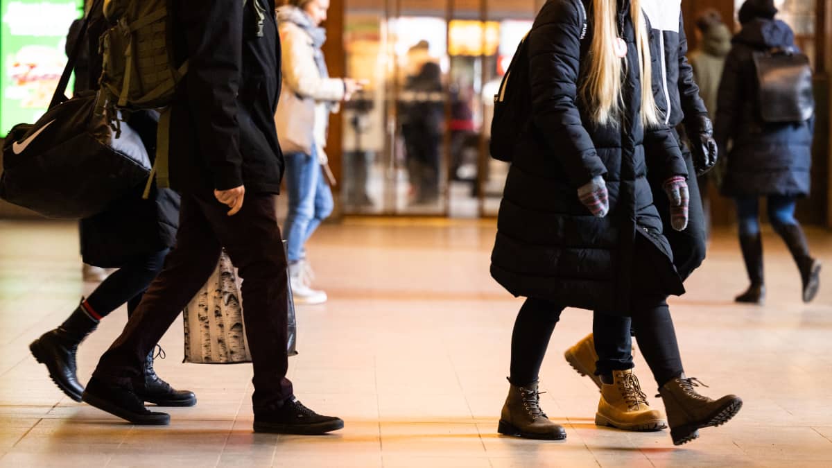 Anonyymit henkilöt kävelevät Helsingin rautatieasemalla.