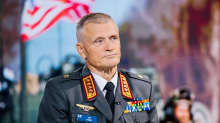 Kenraali Timo Kivinen istuu studiossa taustascreenin edessä.