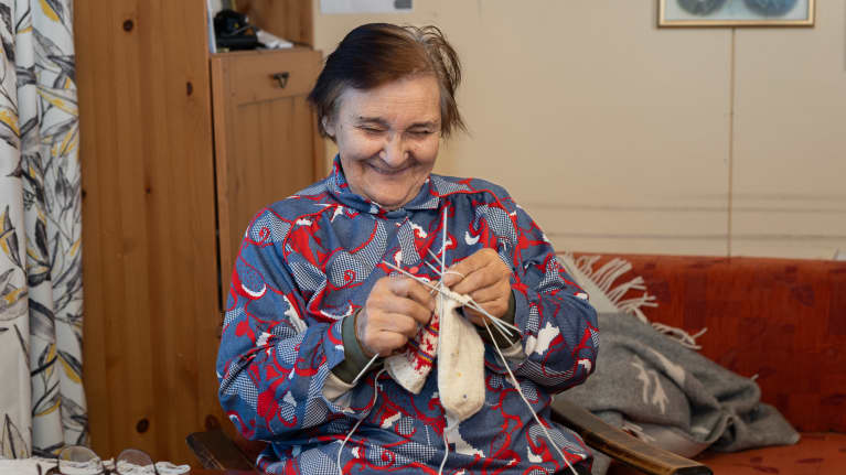 Kuvassa Heijjá-Ánne, Anni Äärelä kutoo sukkia kotonaan Repojoella Inarissa.