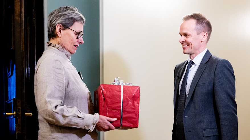 Markku Siponen ojentaa punaisen lahjapaketin kokoomuksen Maaret Castrenille.