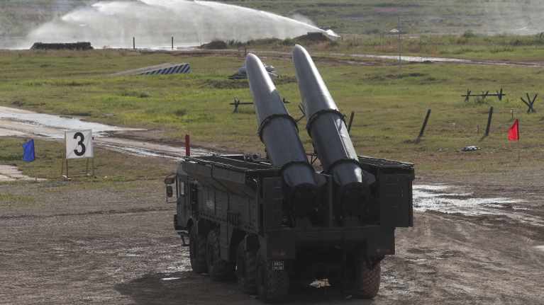 Iskander-M mobile short-range ballistic missile launcher on a military truck in a field.