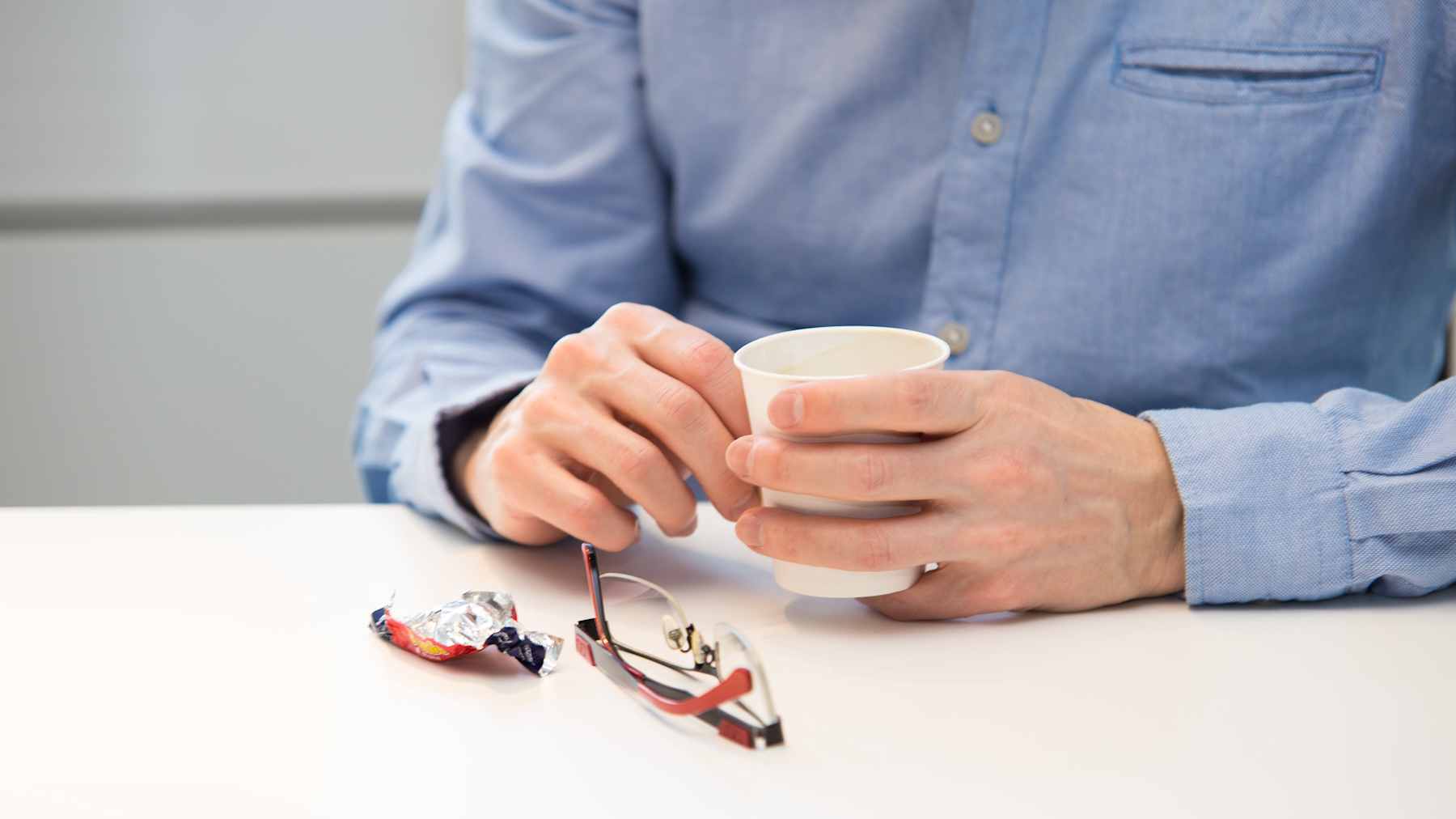 Sami Koiviston käsi kahvikupin ympärillä. Pöydällä karkkipapereita.