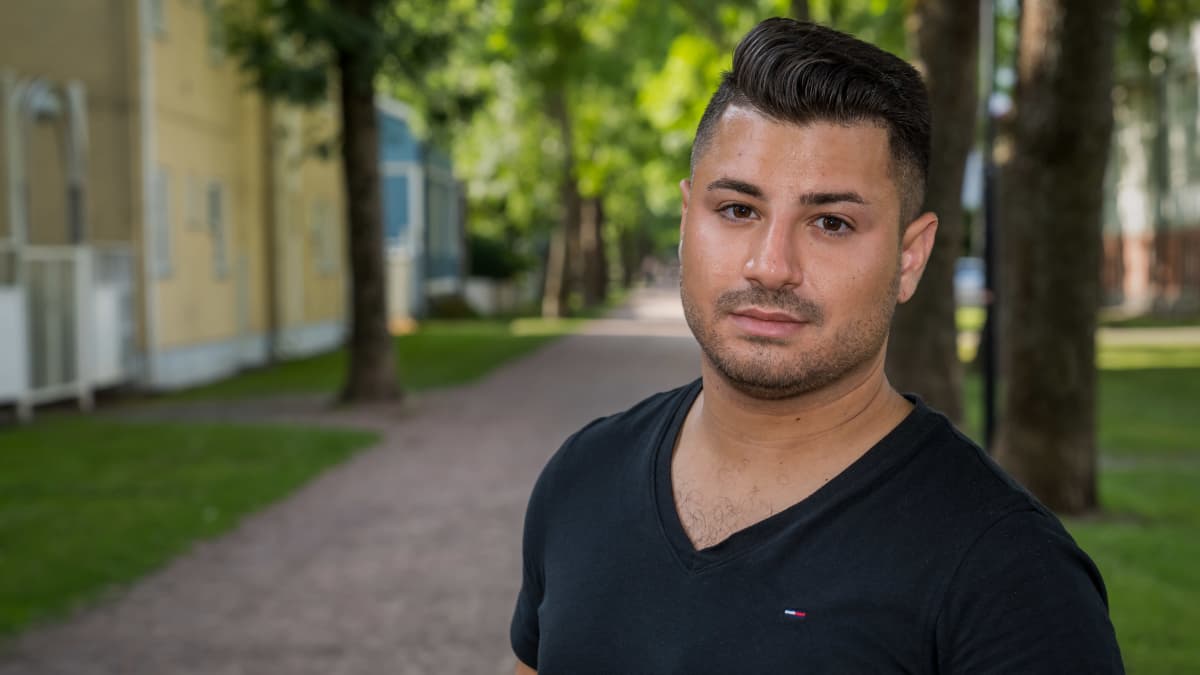 Eric Rimon katsoo kameraan ulkona. Taustalla asuinrakennuksia.