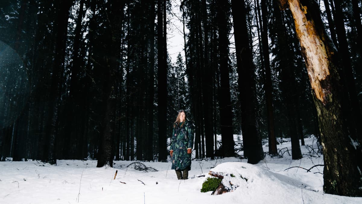 Taina Ihaksi seisoo metsässä.