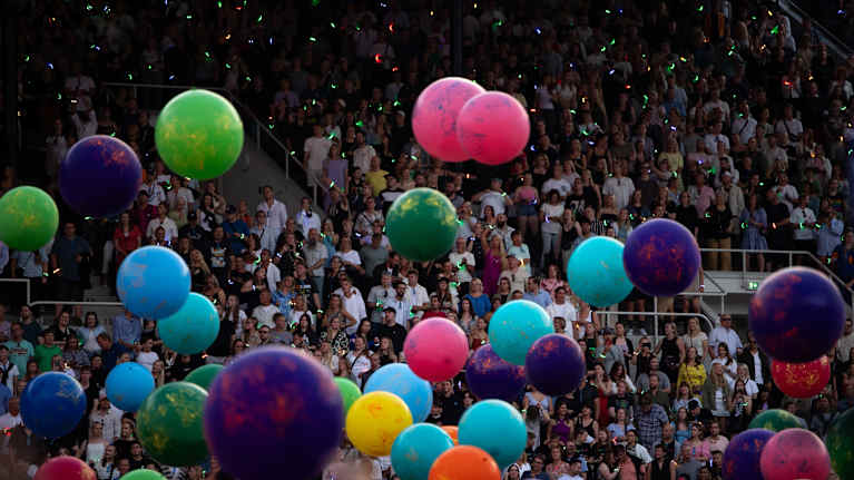Värikkäät pallot pomppivat yleisön joukossa täpötäydellä Olympiastadionilla. Kuva: Lauri Karo / Yle
