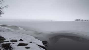 Harmaata maisemaa järven rannalta. Jäät ovat lähtemässä vähitellen. 