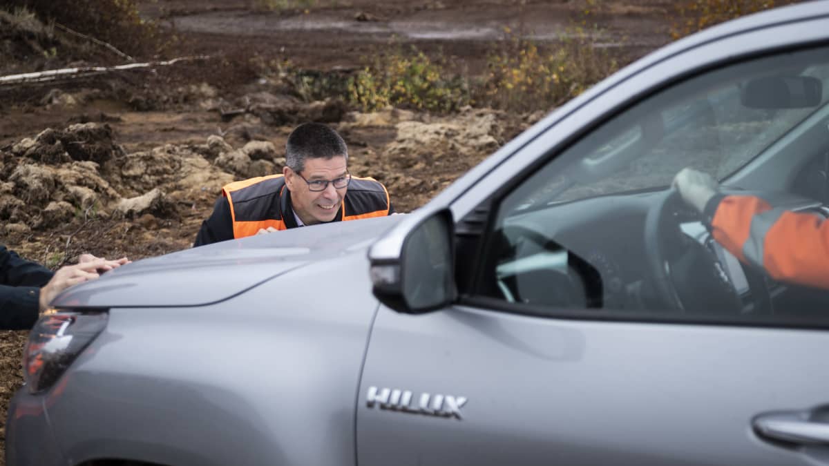 Hannu Hautala työntää turvesuohon juuttunutta autoa. 