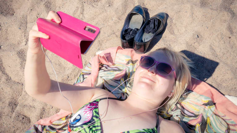 Jenni Hänninen katselee videota rannalla.