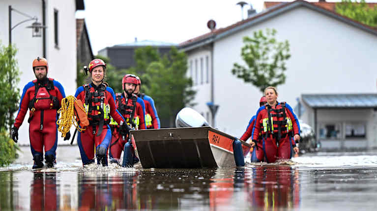 Pelastustyöntekijät kahlaavat tulvavedessä kadulla.