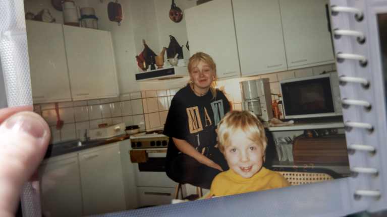 Paperivalokuva, jossa on valkoinen 70-luvun keittiö ja siellä istuu nuori tyttö ja ja pikku poika.