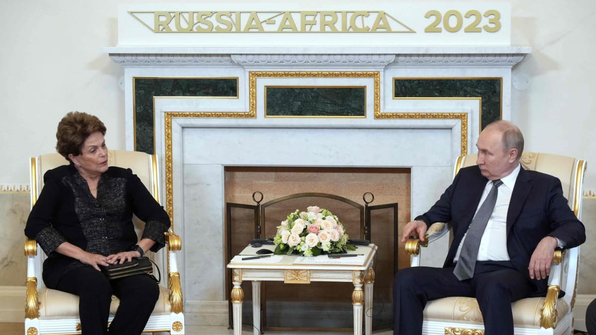 Dilma Rousseff ja Vladimir Putin istuvat koristeelllisilla tuoleilla takan edustalla, jonka yllä lukee Russia-Africa 2023.