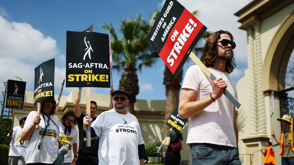 Mielenosoittajat kävelevät kylttien kanssa, joissa lukee muun muassa "SAG AFTRA ON STRIKE!"
