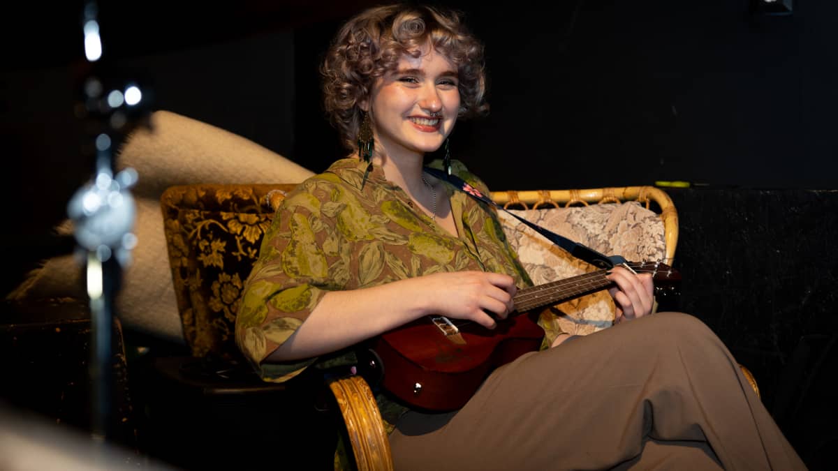Noora Kivelä istumassa tuolilla ukulele sylissä.