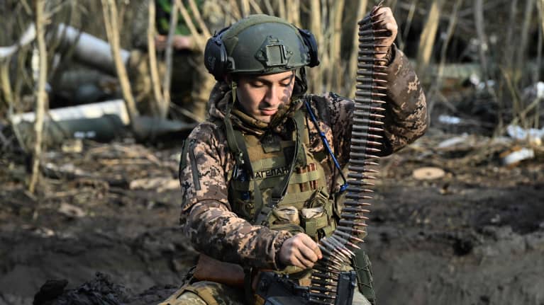 Ukrainalaissotilas lataamassa konekiväärin panosvyötä.