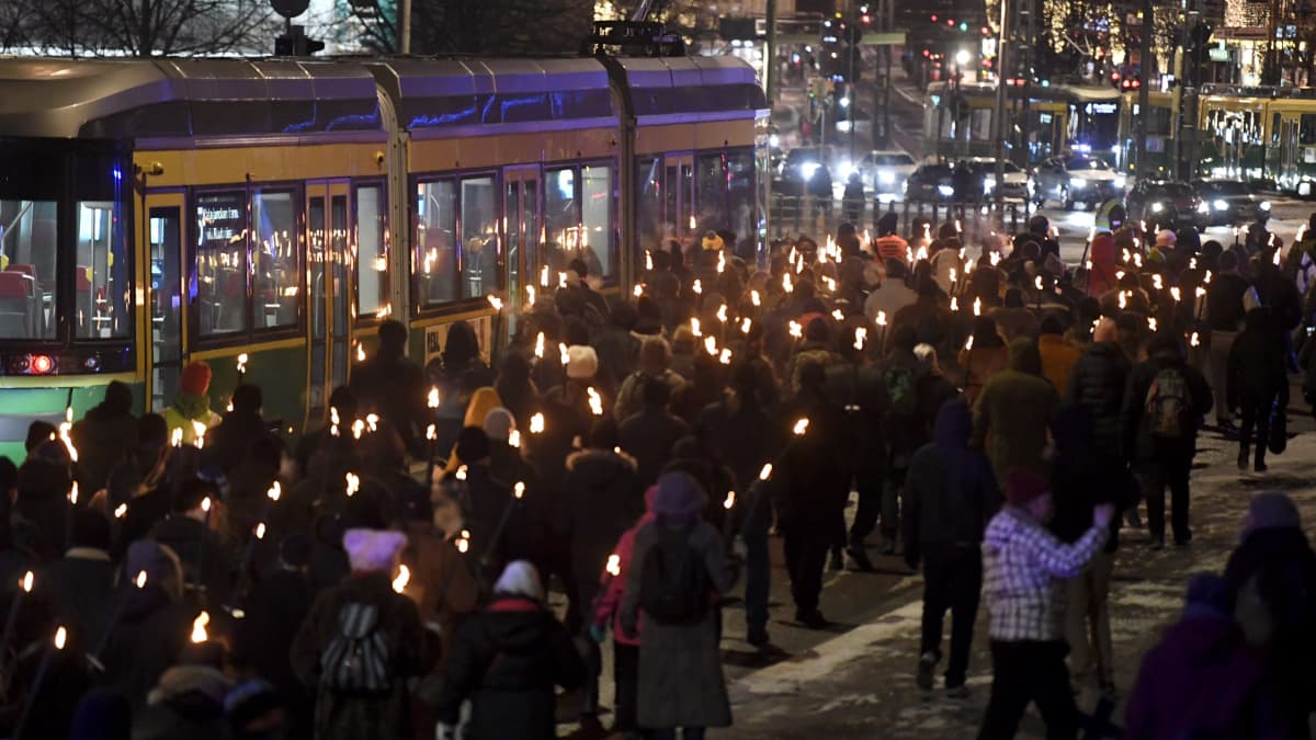 En större grupp människor deltar i ett fackeltåg i Helsingfors centrum längs Mannerheimvägen på självständighetsdagen 2021. 
